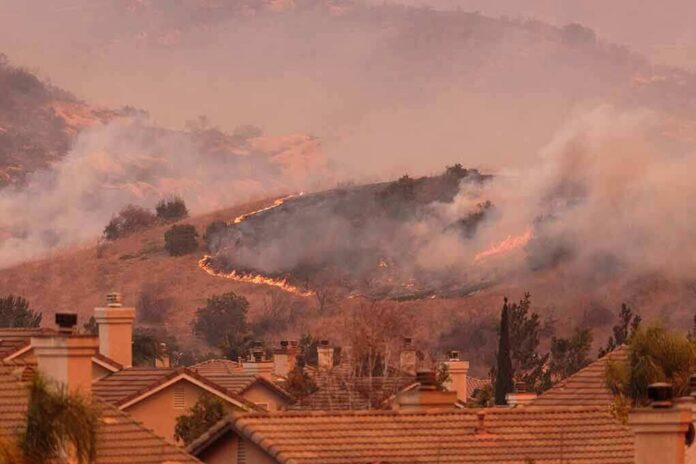 Wildfire burns on hillside near suburban homes