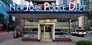 NYPD precinct building with signs on a city street