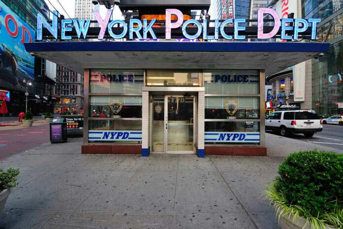 NYPD precinct building with signs on a city street