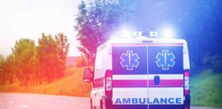 Ambulance van with flashing lights on a rural road