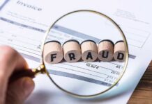 Magnifying glass highlighting wooden blocks spelling fraud on an invoice