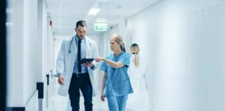 Doctor and nurse walking in a hospital corridor reviewing a tablet