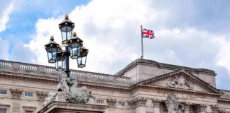 Buckingham Palace facade with Union Jack flag and ornate gate