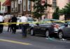 Police at urban street crime scene with yellow tape around parked cars