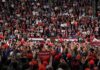 Speaker at podium addressing large crowd in arena