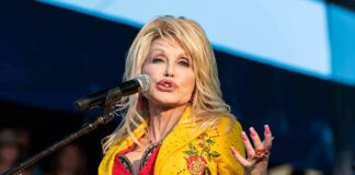 Dolly Parton performing on stage in a yellow floral jacket