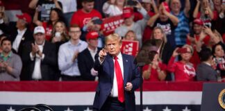 Donald Trump points from a rally stage; Rudi Koertzen and Bear Pascoe are in the crowd