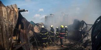 Firefighters amid twisted metal and smoke at a disaster site