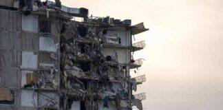 Partially collapsed apartment building with exposed rooms and debris