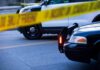 Police cars behind yellow caution tape at a street scene