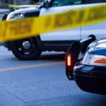 Police cars behind yellow caution tape at a street scene