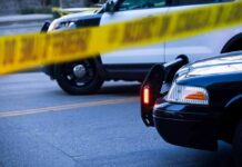Police cars behind yellow caution tape at a street scene