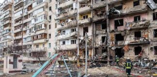 Damaged apartment building behind a playground slide