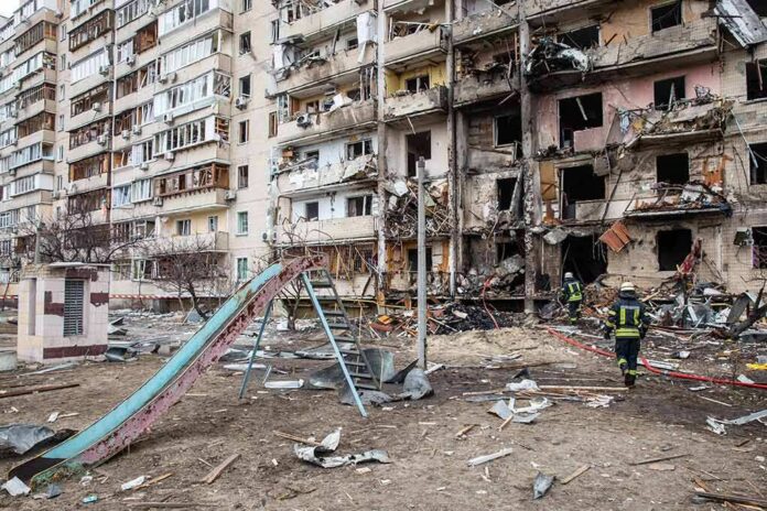 shutterstock_2129012939 Damaged apartment building behind a playground slide