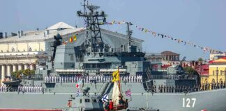 Military ships in a naval parade on a city waterfront