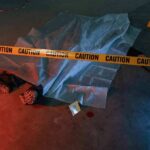 crime scene body under sheet behind caution tape