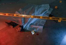 crime scene body under sheet behind caution tape