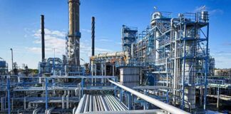 Industrial refinery with pipelines and distillation towers under blue sky