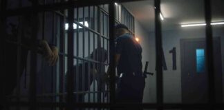 police officer at a jail cell with detainees behind bars