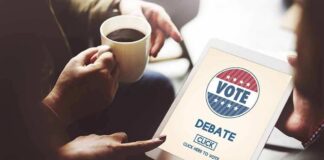 Hands holding a tablet with a voting screen and a person holding coffee