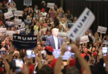 Ballot Bombshell: Trump Demands Center Stage man at podium addressing a large crowd at a rally