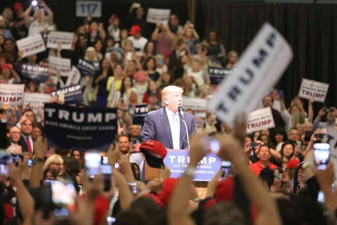 man at podium addressing a large crowd at a rally