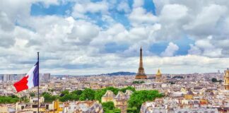 Eiffel Tower over Paris skyline with French flag in foreground