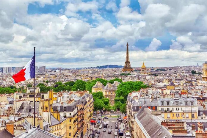 Eiffel Tower over Paris skyline with French flag in foreground
