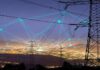 Power transmission towers over a city at dusk with connected network lines