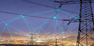 Power transmission towers over a city at dusk with connected network lines