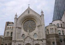 Silenced Priest Sparks Canon Law Fight Stone church facade with large rose window and cross