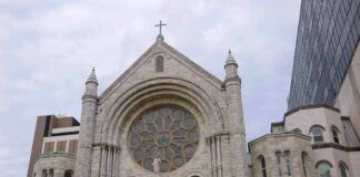 Stone church facade with large rose window and cross