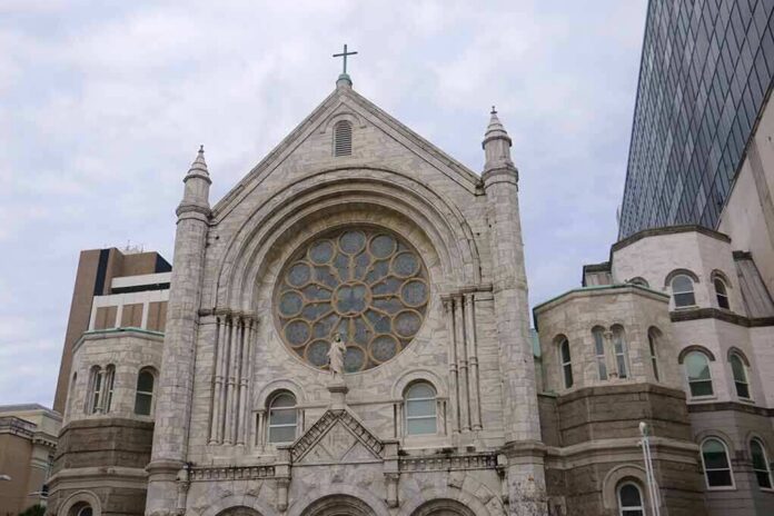 Stone church facade with large rose window and cross