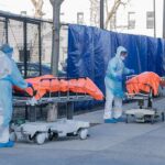Russia Quarantines Hundreds After Lab Shock Healthcare workers in PPE move covered stretchers outside a facility