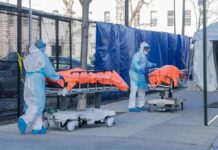 Russia Quarantines Hundreds After Lab Shock Healthcare workers in PPE move covered stretchers outside a facility