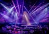 Concert stage with performers under purple laser lights