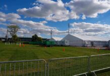 Truck Plows Youth Game – Horror In Wichita Temporary white tents and equipment on a grassy field with traffic cones and metal barriers