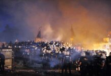 Riot police gather amid smoke at night