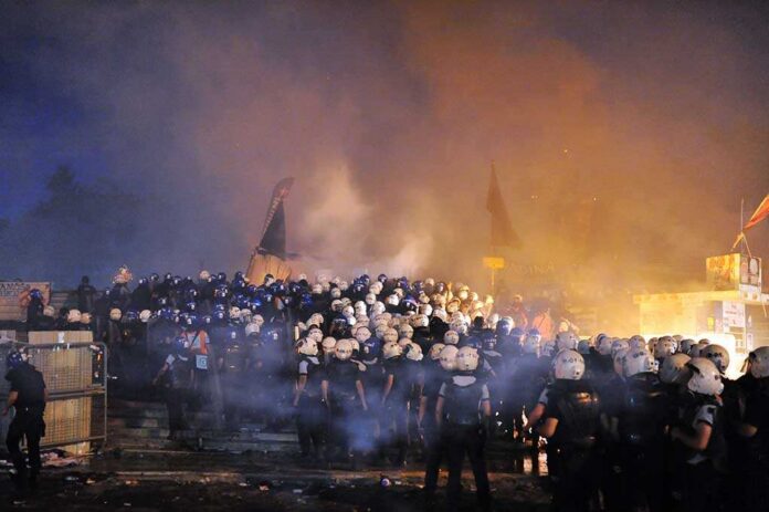 Riot police gather amid smoke at night