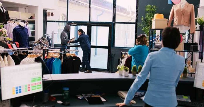 shutterstock_2348378987-1 Clothing store interior with staff near entrance during tense incident