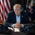 Backlash Erupts – Trump Axes Live Execution Donald Trump seated at a table between two desk phones