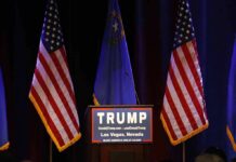 Trump Turns Up Heat In Georgia Podium with campaign sign between American flags